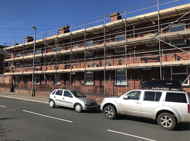 A row of red-brick terraces in Armley under scaffolding