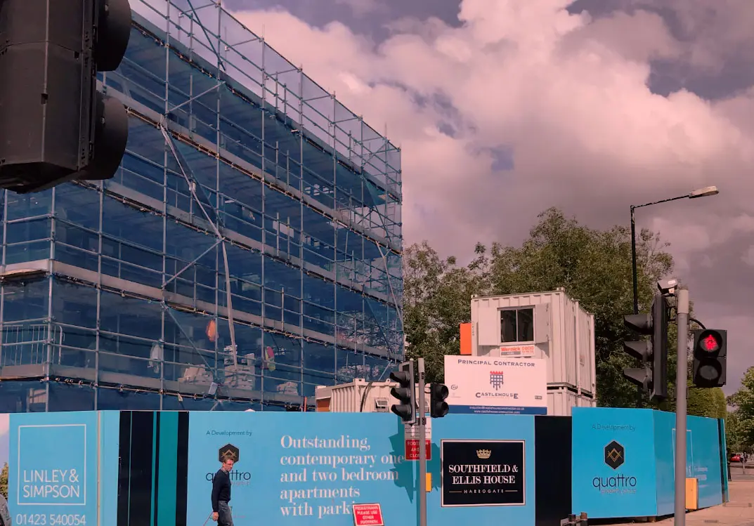 Southfield & Ellis House under construction behind branded hoarding on Station Parade